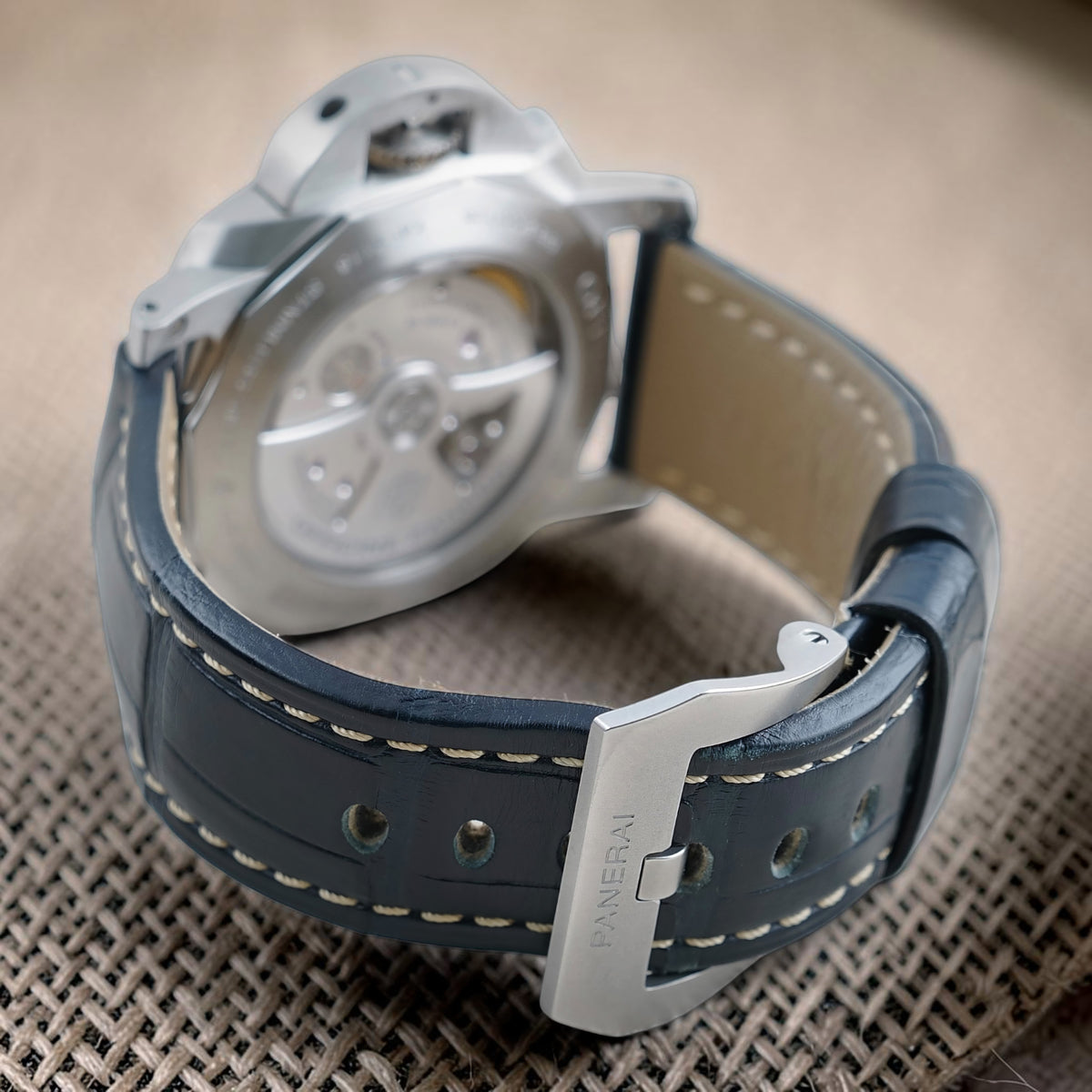 Panerai Luminor GMT PAM01033 rear view with exhibition caseback, blue stitched strap and signed Panerai buckle
