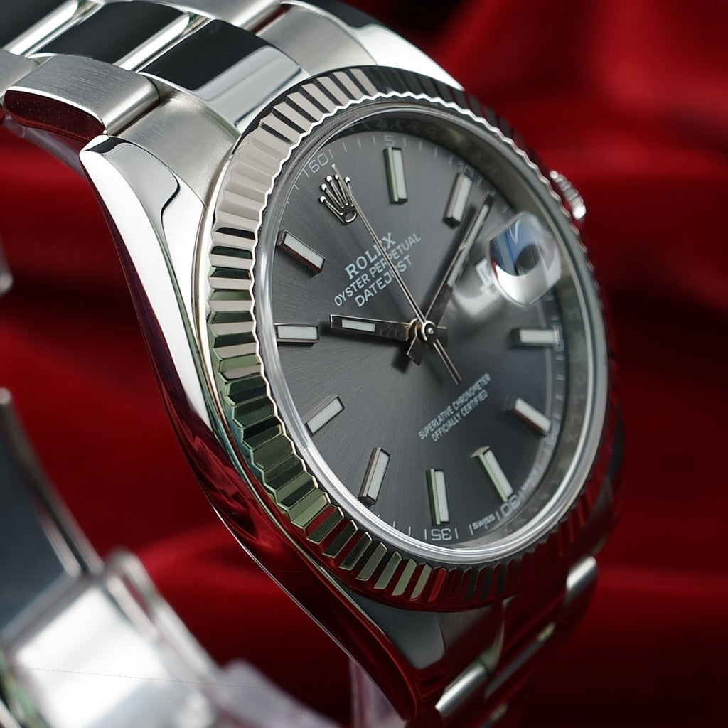 Close-up of Rolex Datejust 41 126334 slate stick dial, date magnifier and fluted bezel against a red background.