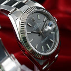 Close-up of Rolex Datejust 41 126334 slate stick dial, date magnifier and fluted bezel against a red background.