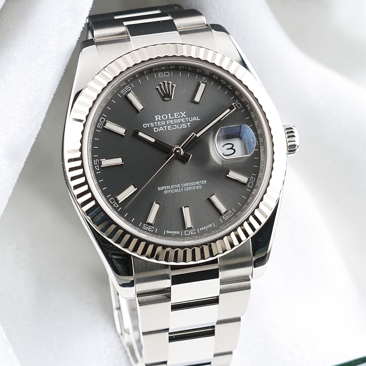Front view of Rolex Datejust 41 126334 with slate stick dial, fluted bezel and Oyster bracelet on white fabric.