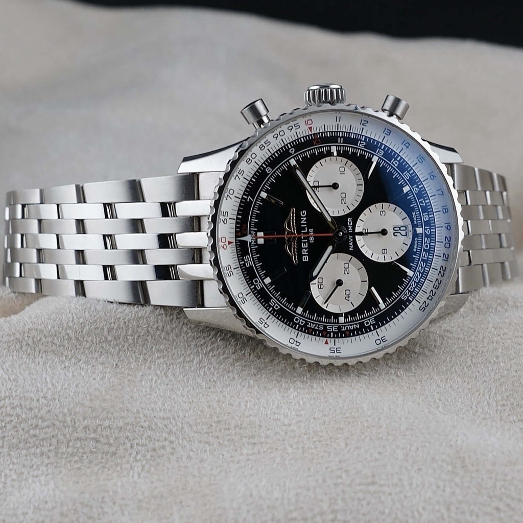 Wrist Flex Timepieces Breitling Navitimer B01 chronograph watch with black reverse panda dial and steel bracelet.