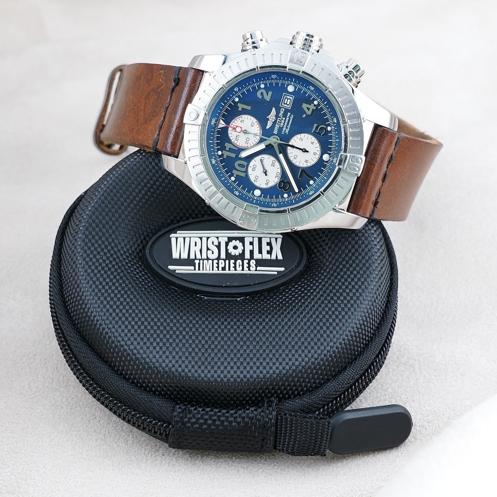 Wrist Flex Timepieces Breitling Super Avenger chronograph with blue dial and brown leather strap on a travel case