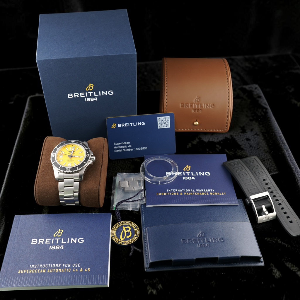 Wrist Flex Timepieces Breitling Superocean Automatic 44 with yellow dial, box, warranty card, and extra rubber strap.